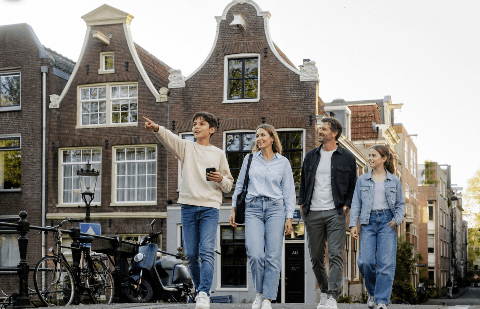 A family walking an Amsterdam canal street, phone in hand, with the Artis and Van Gogh Museum coins from Treasures of Amsterdam